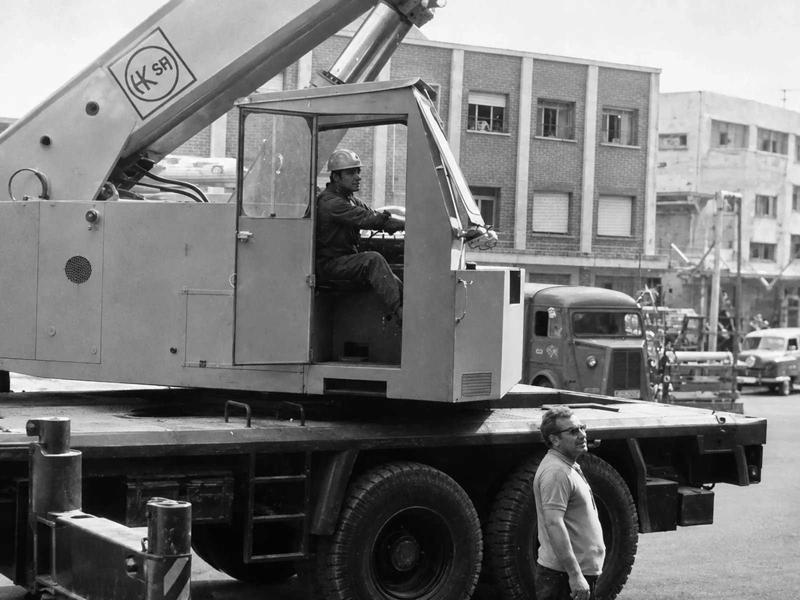 Operador de Grúas Polisol en la cabina de una grúa autopropulsada junto a otro compañero, en una obra urbana de Cartagena